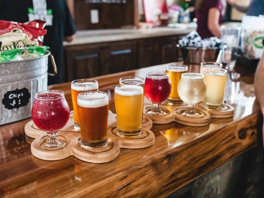 Beer flights of red, amber and pale beers on wooden paddles at a taproom bar