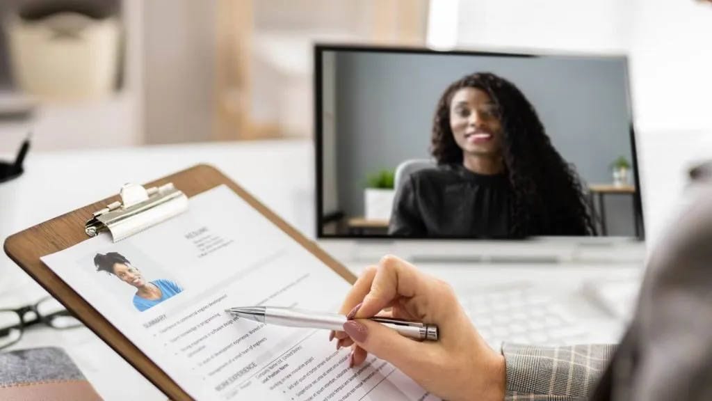 Property manager reviewing an applicant's resume on a clipboard during a video interview